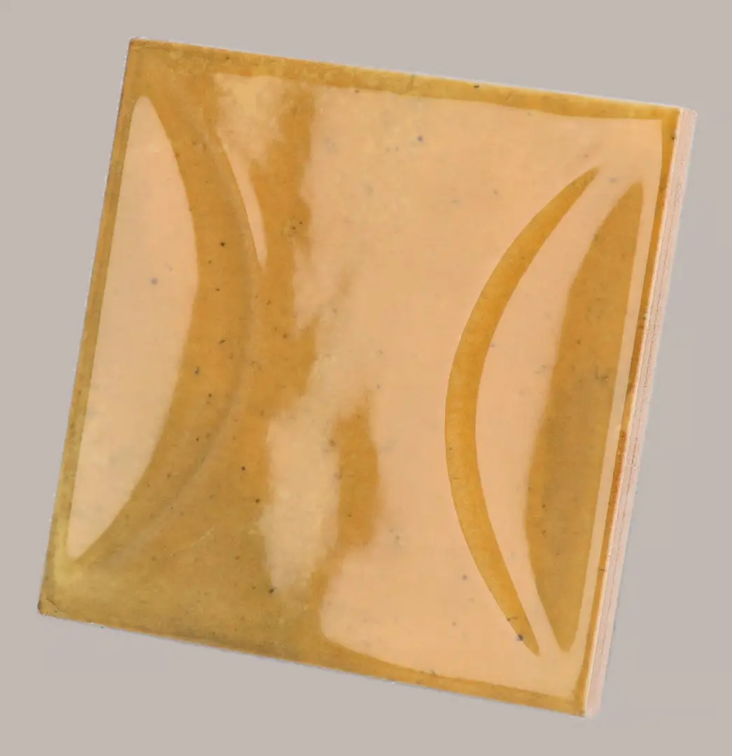 Hanoi Wandfliese in Caramel Glasur, Format 10x10 cm, schräge Studio Aufnahme mit sichtbarem Glasurglanz.