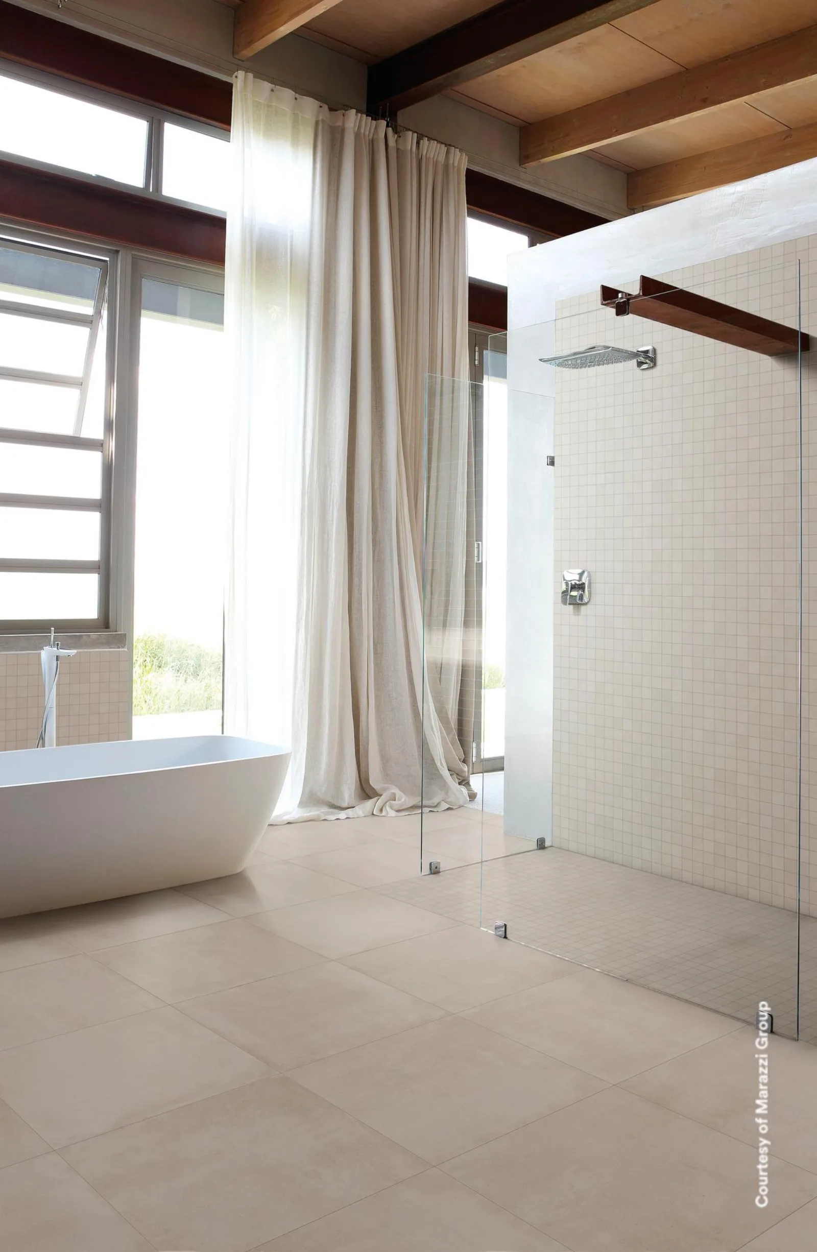 Badezimmer mit freistehender Wanne, Vorhang am Fenster und bodengleicher Dusche, heller Boden.