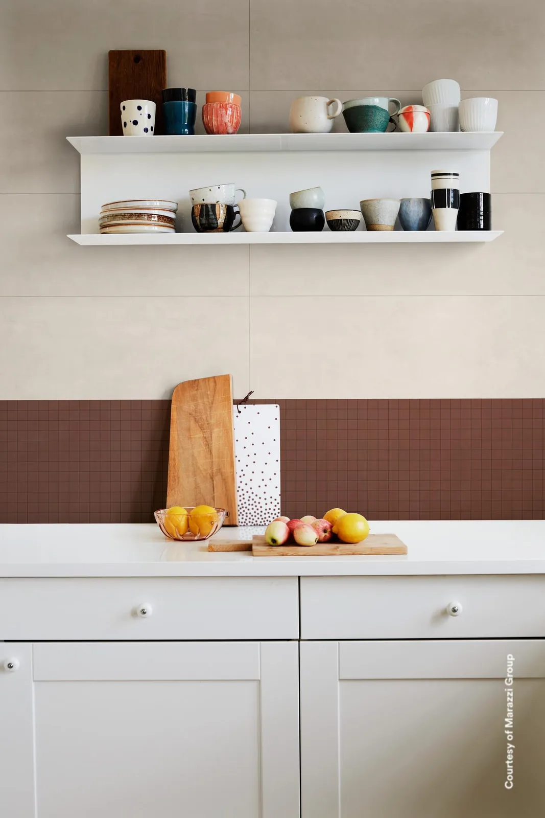 Küche mit hellen Wandfliesen über weißen Schränken und einem Band aus braunem Mosaik als Spritzschutz