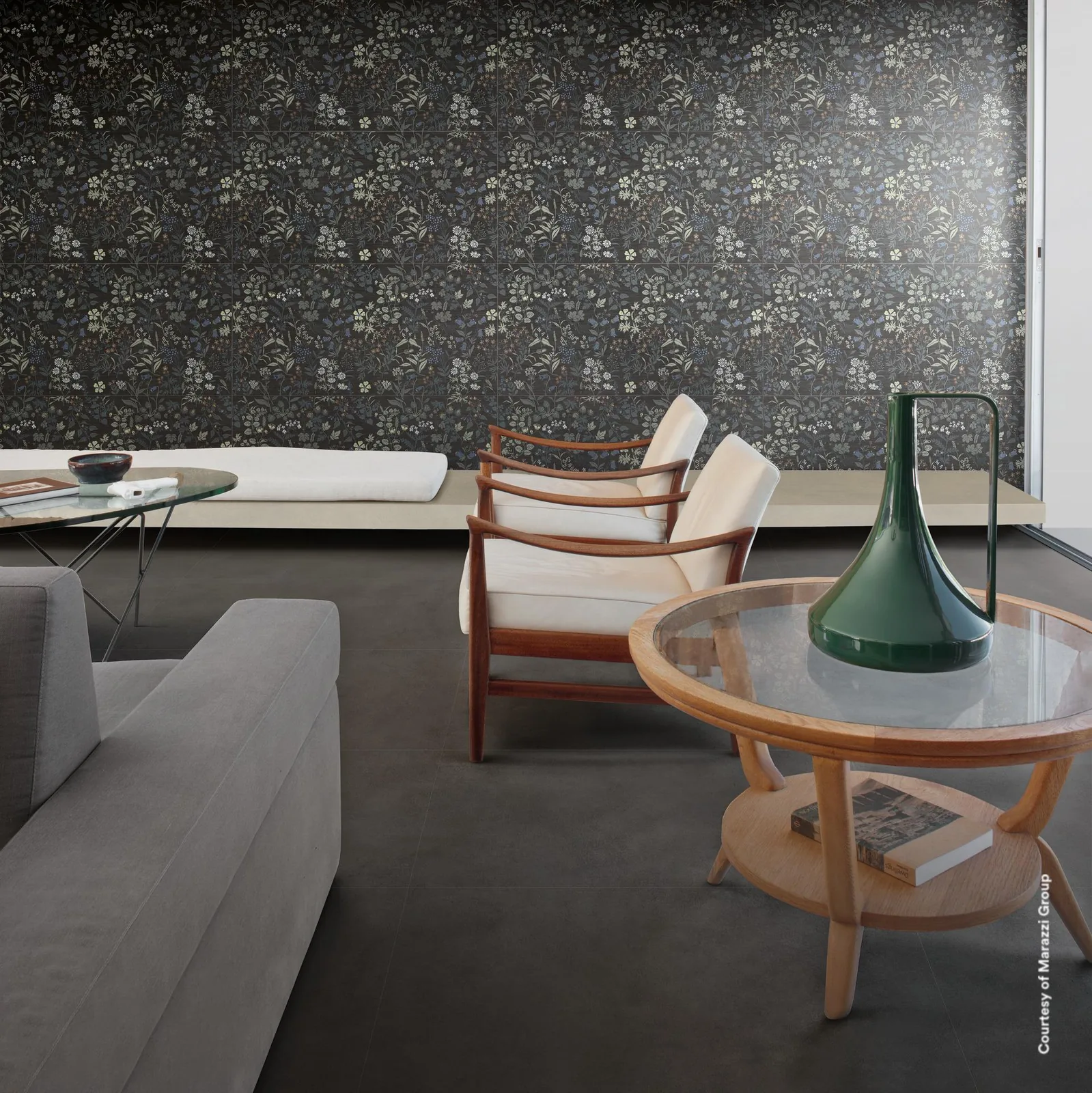 Wohnraum mit dunkler Blumenmuster-Wand hinter Sofa und Sesseln, dazu ein anthrazitfarbener Betonoptik-Boden.