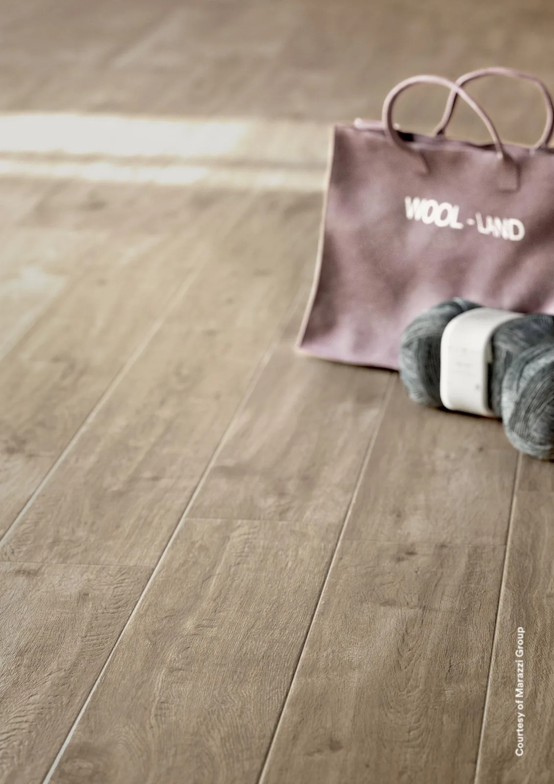 Strickbeutel mit Wollknäueln auf einem Boden aus Holzoptik-Dielen in natürlichem Mittelbraun