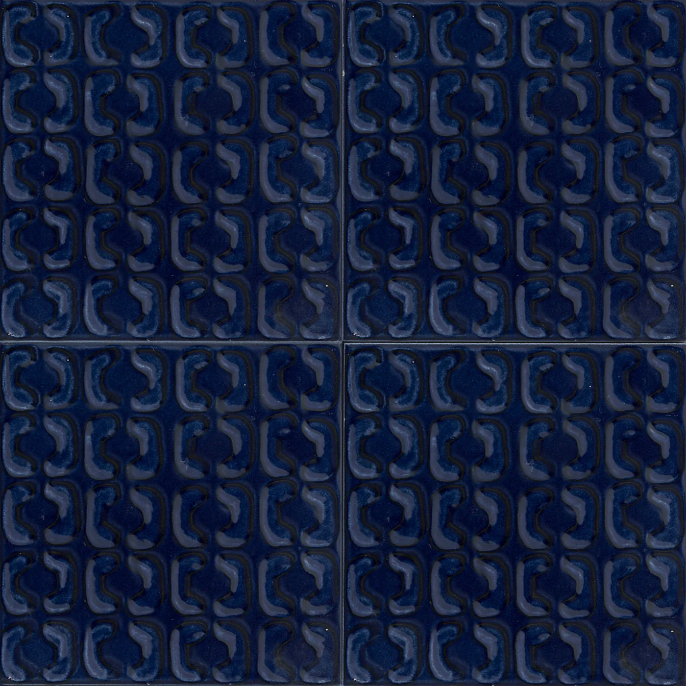 Vier dunkelblaue Reliefliesen 15x15 cm, seidenmatt, mit erhabenem Muster aus ineinandergreifenden Bogenformen.
