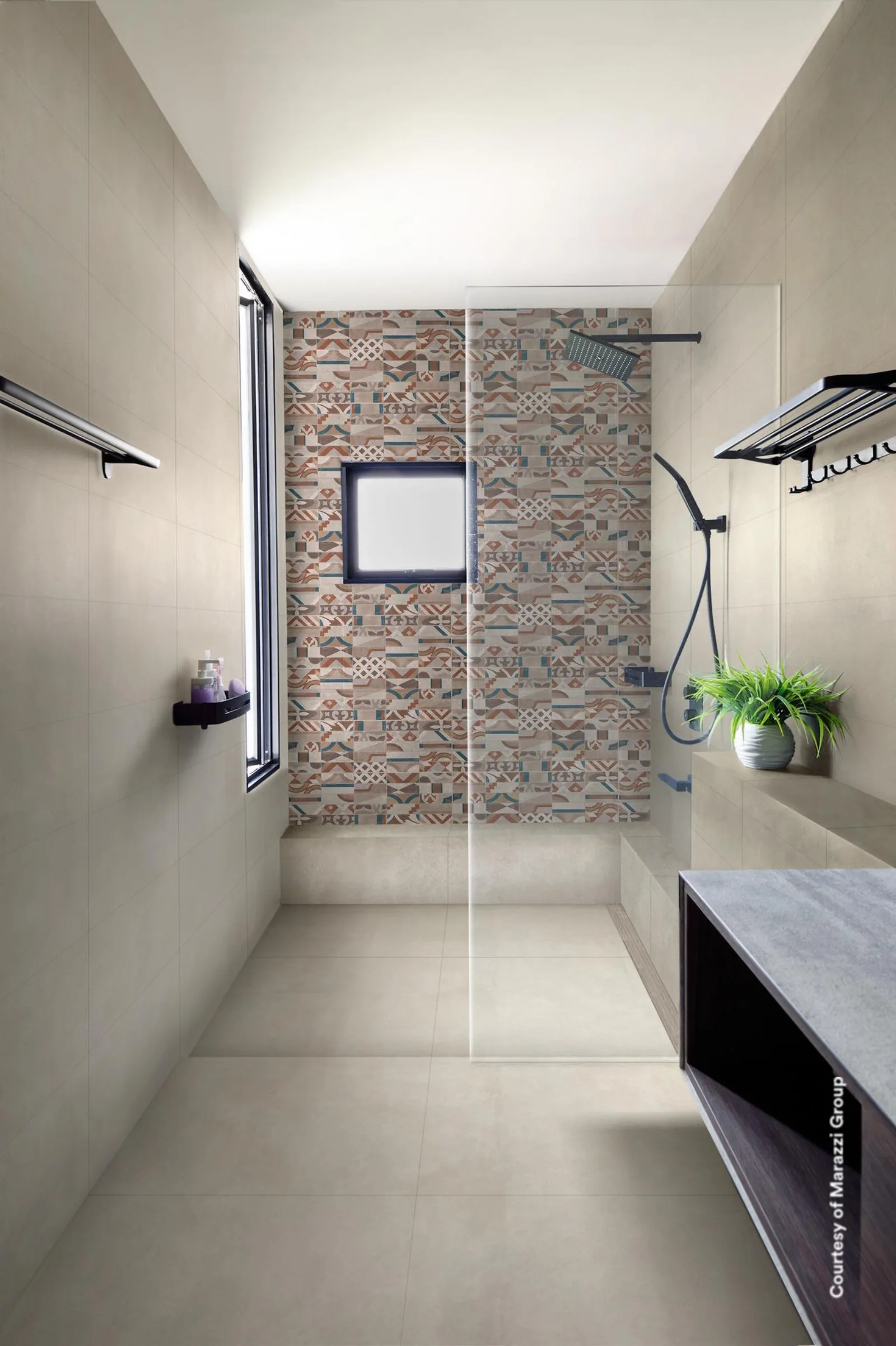Schmales Bad mit Dusche, Handtuchhaltern und bunt gemusterter Fliesenwand in der Raummitte.