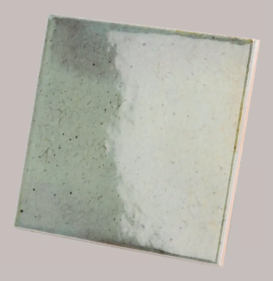 Hanoi Wandfliese in Celadon Glasur, Format 10x10 cm, schräge Studio Aufnahme mit sichtbarem Glasurglanz.
