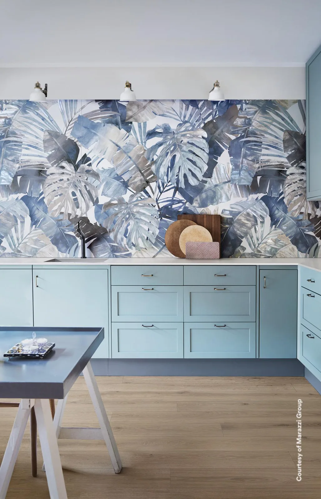 Küche mit hellblauen Unterschränken, die Wand darüber durchgehend mit großen blaugrauen Tropenblättern gefliest.