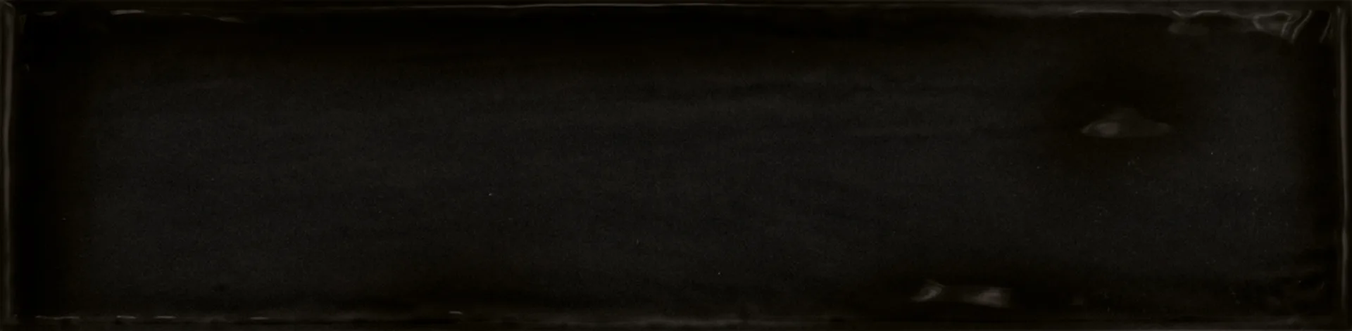Einzelne schwarze Rechteckfliese mit matter Glasuroberfläche im Format 7,5×30 cm und sanften Lichtreflexen.