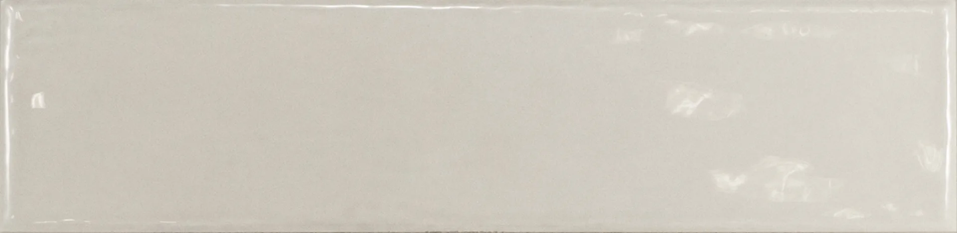 Einzelne hellgraue Rechteckfliese mit glänzender Glasuroberfläche im Format 7,5×30 cm und sanften Lichtreflexen.