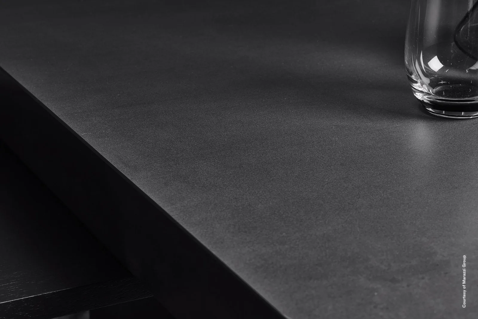 Tischplatte aus Marazzi Grande Metal Look Iron Dark in Metalloptik, matt anthrazit, mit Wasserglas