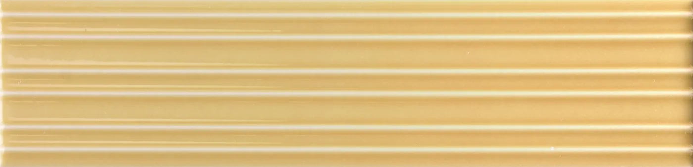 Rechteckige Wandfliese in goldenem Ockerbeige, glänzend, mit parallelem Rillenrelief, im Format 6x24,6 cm.