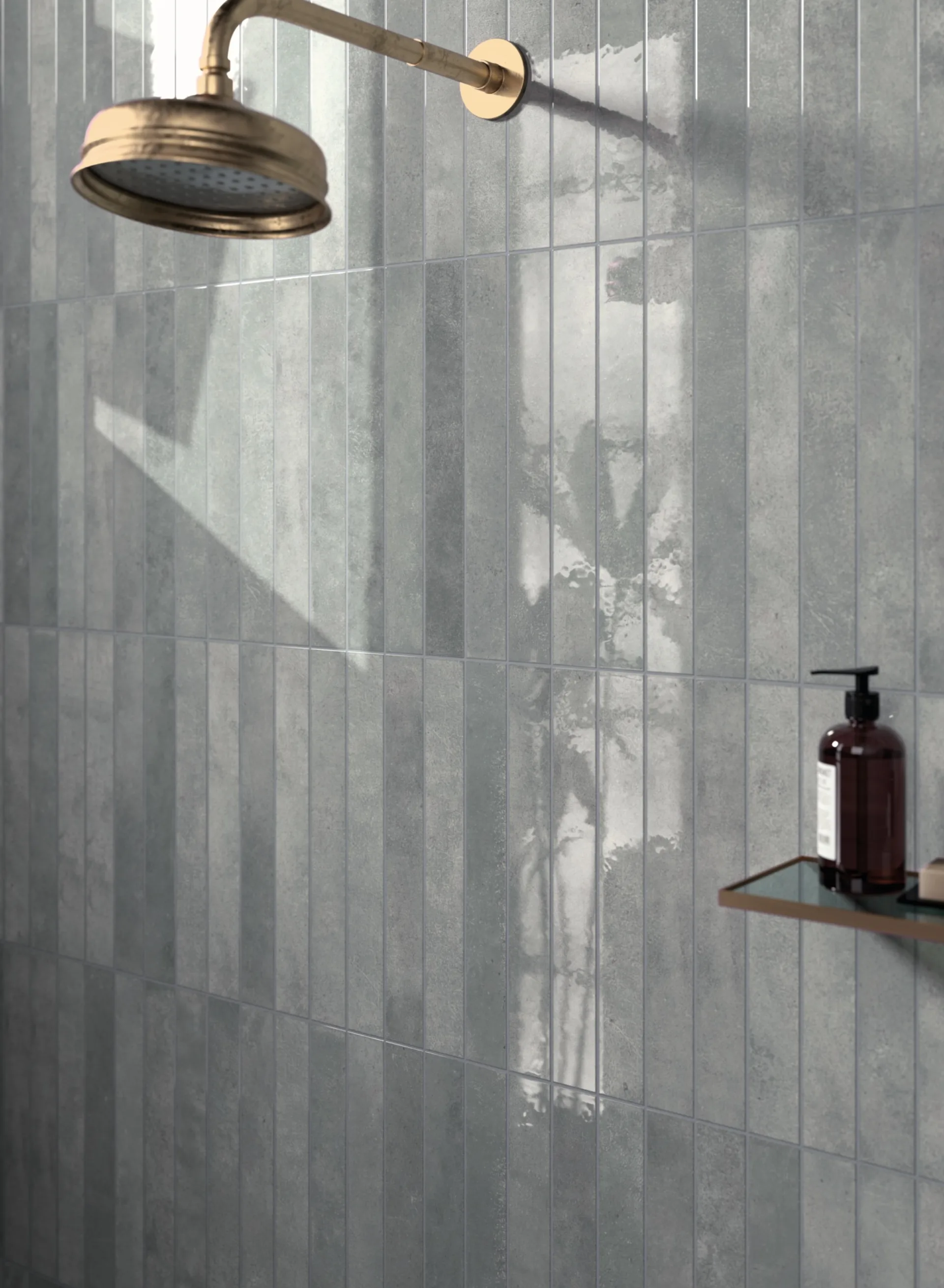 Dusche mit grauen, senkrechten Riemchen, bronzefarbener Regenbrause und Seifenspender auf Ablage.