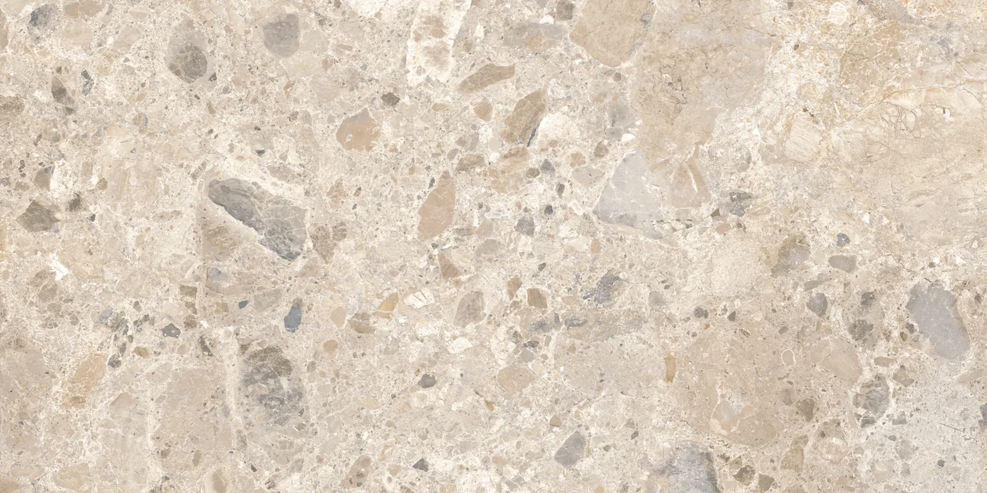 Cremefarbene Fliese 60×120 cm in Terrazzo-Optik mit beigen, grauen und braunen Steinsplittern unterschiedlicher Größe.