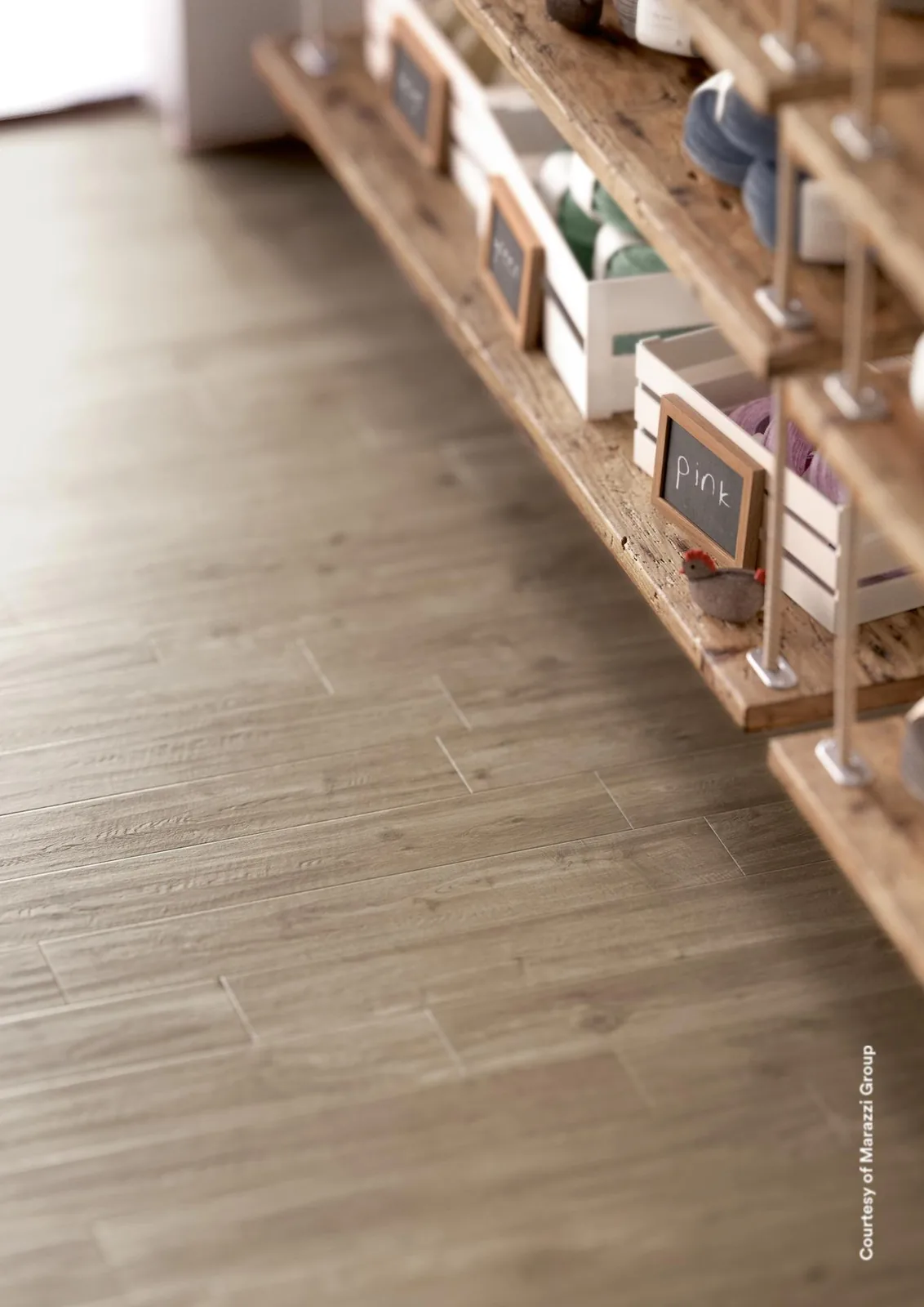Flache Ansicht eines Bodens aus Holzoptik-Dielen in Mittelbraun vor einem Holzregal mit Kisten