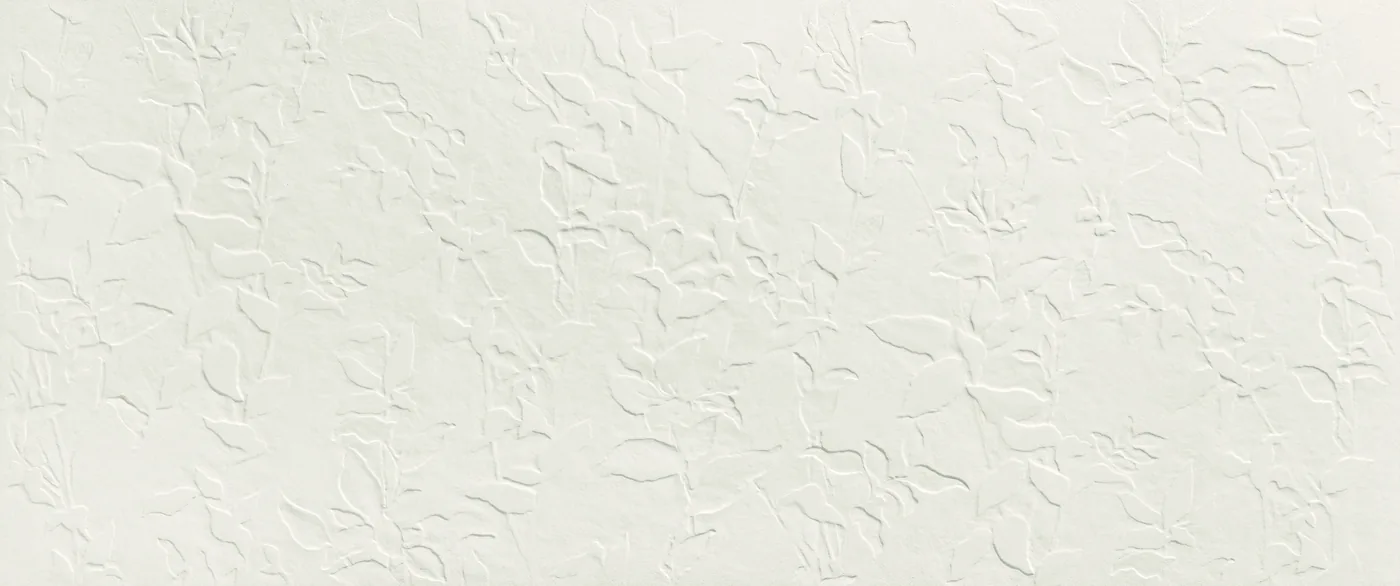 Weiße Wandfliese 50×120 cm matt mit fein verstreutem Relief aus kleinen Blüten und Blättern über die Fläche.