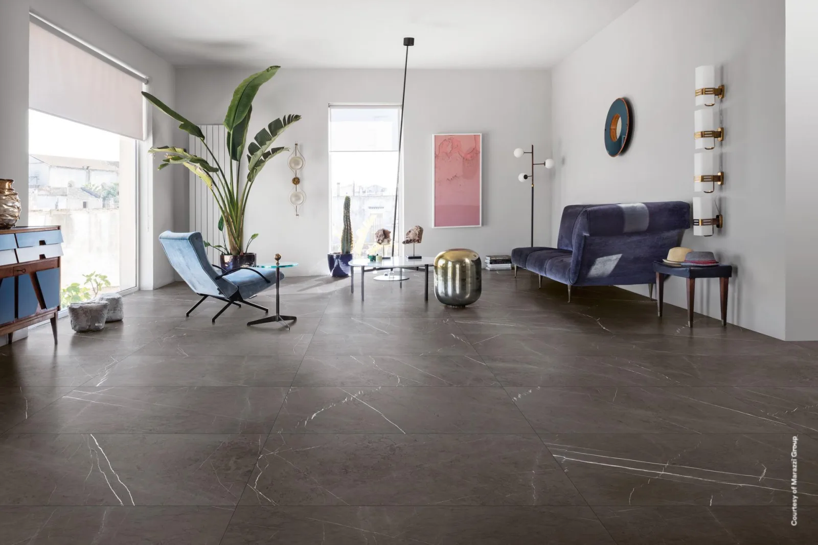 Heller Wohnraum mit dunkelgrauem Marmorboden Allmarble Imperiale 60x120 cm, blauem Sofa und bodentiefer Fensterfront