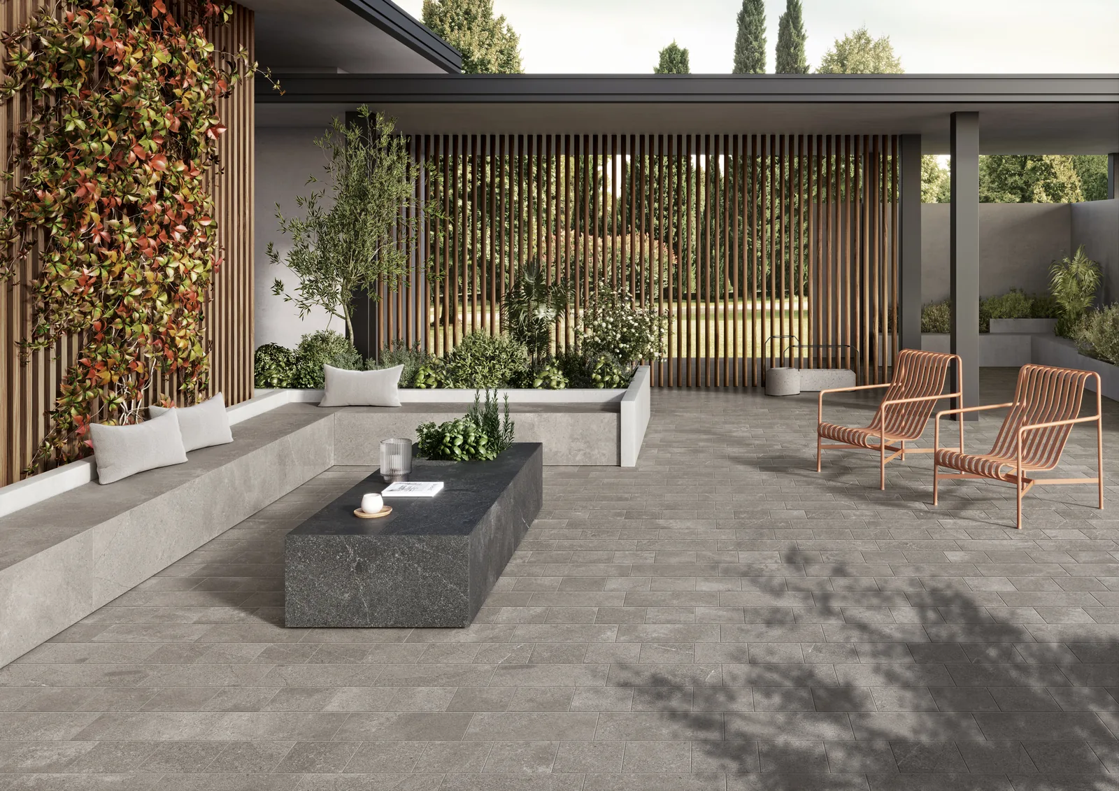 Überdachte Terrasse mit grauen Steinoptik-Fliesen im Kleinformat, Lounge-Sitzbank, Pflanzwand und Korbsesseln.