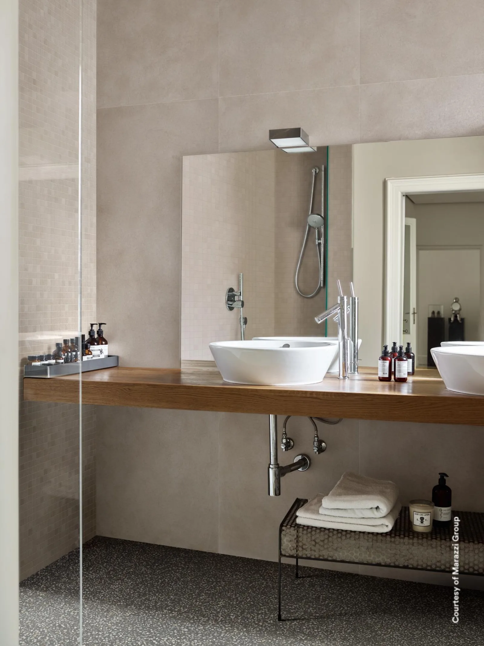 Bad mit Marazzi Alchimia Greige 60x180 cm: ruhige Mikrozement-Wand ueber Holz-Waschtisch, Mosaikstreifen an der Dusche.