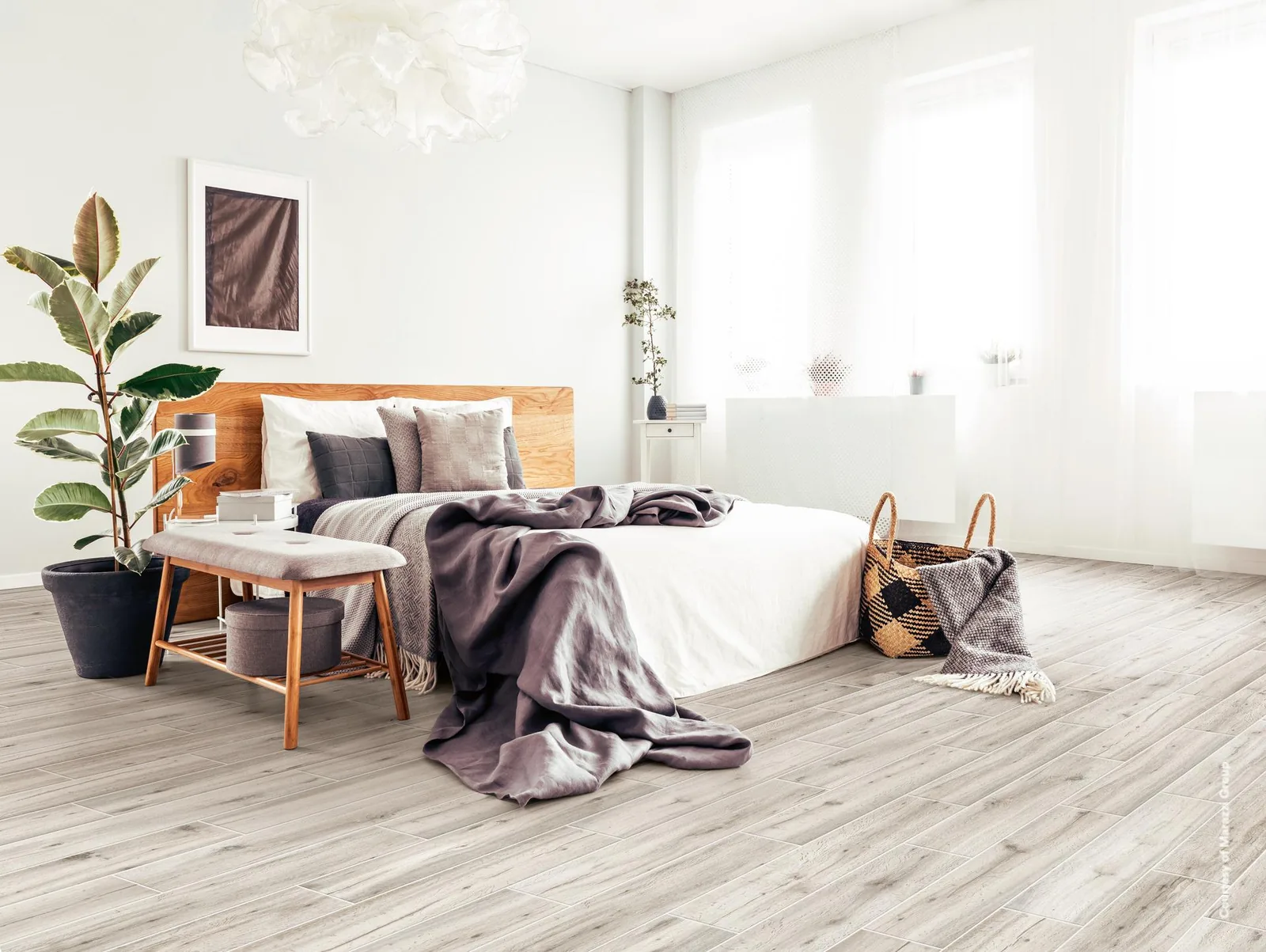 Helles Schlafzimmer mit Bett, Holzbank und Pflanzen, der Boden mit weißgrauen Holzoptik-Dielen längs verlegt.