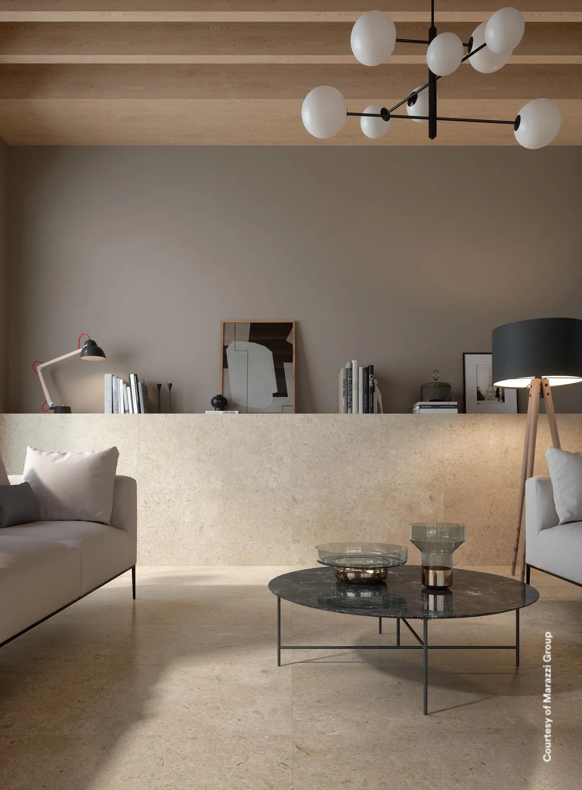 Wohnraum mit grauem Sofa und rundem Couchtisch, Boden und Wand in greigefarbener Steinoptik mit Holzdecke.