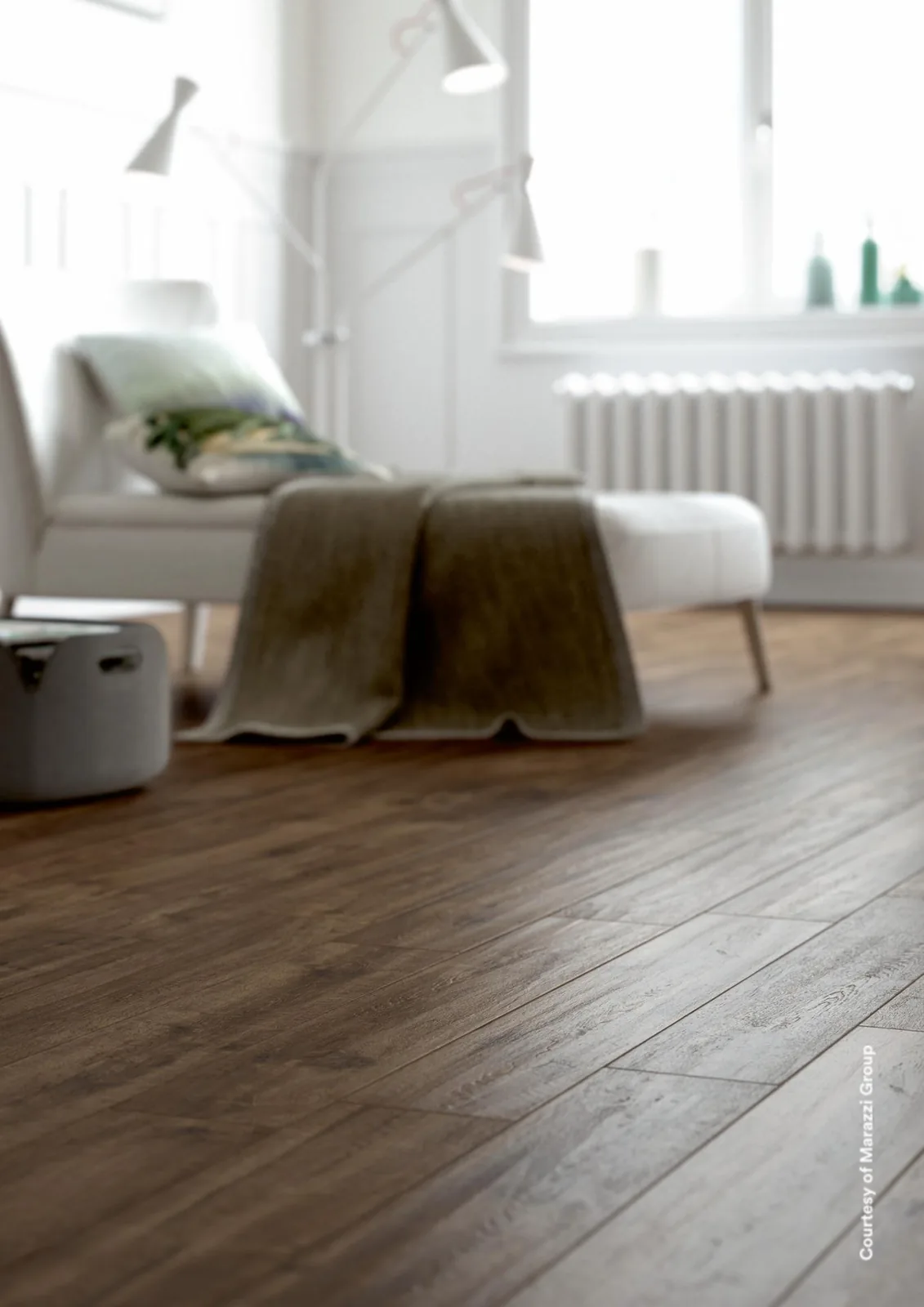 Weißer Sessel mit Decke vor Heizkörper und Fenster, Boden aus Holzoptik-Dielen in dunklem Graubraun