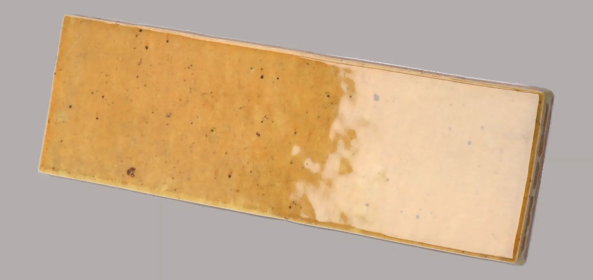 Hanoi Wandfliese in Caramel Glasur, Format 5,1x16,1 cm, schräge Studio Aufnahme mit sichtbarem Glasurglanz.