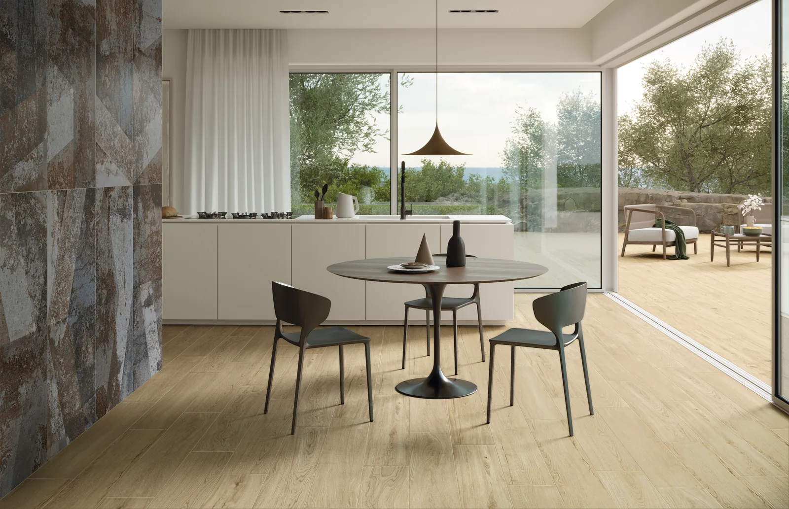 Essbereich mit hellem Holzoptik-Boden, rundem Tisch, dunklen Stühlen und großer Glasfront zum Garten