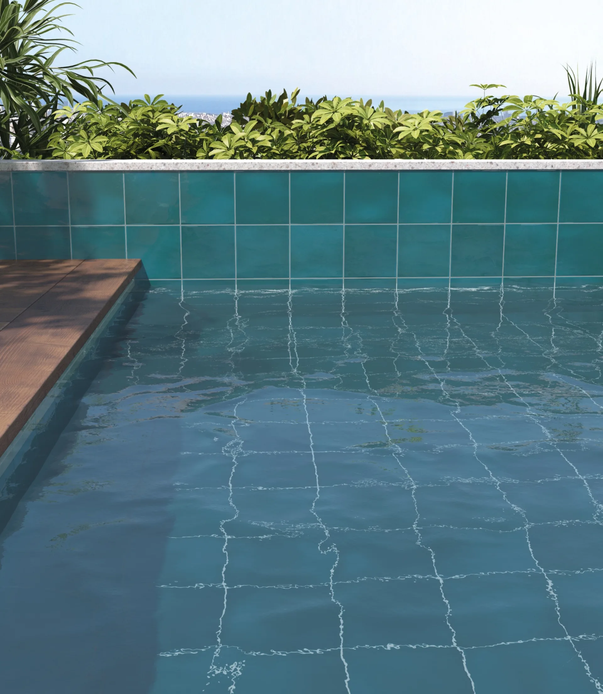 Türkisfarbenes Poolbecken mit glänzenden Fliesen und Blick über Grün auf das Meer im Hintergrund.