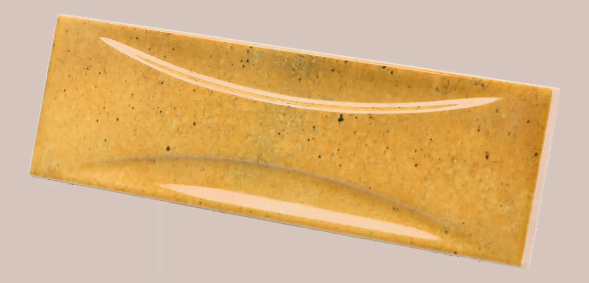 Hanoi Wandfliese in Caramel Glasur, Format 6,5x20 cm, schräge Studio Aufnahme mit sichtbarem Glasurglanz.